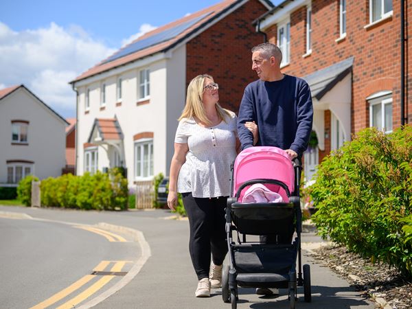Smiling couple pushing pram on a Persimmon development